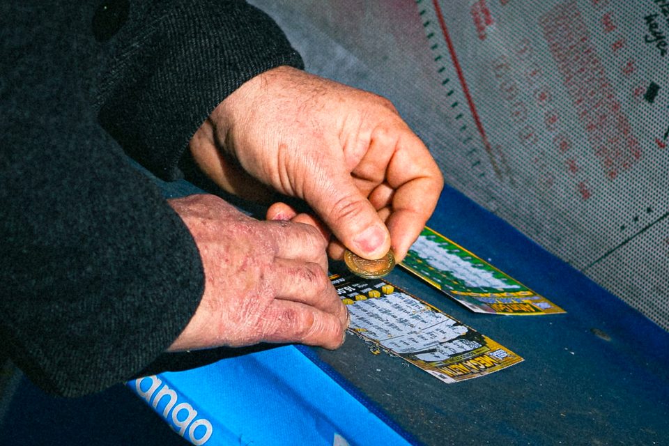 Scratching a lottery scratch card with a coin