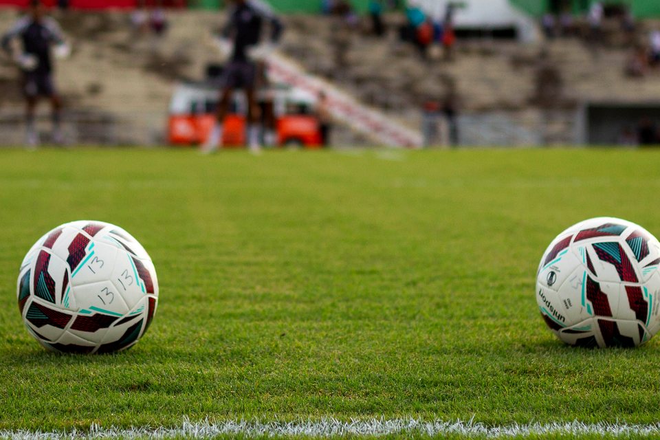 Two footballs on a green pitch