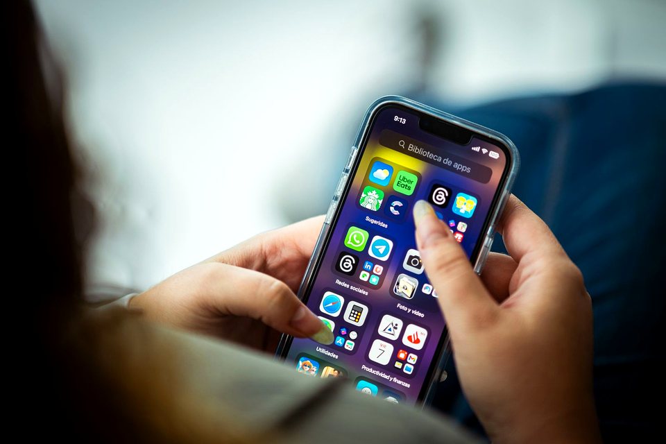 Hands holding a smartphone with apps on screen